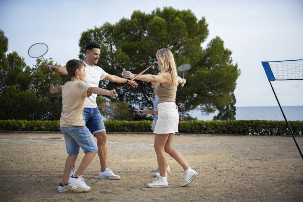 young couple playing in badminton courts with their kids